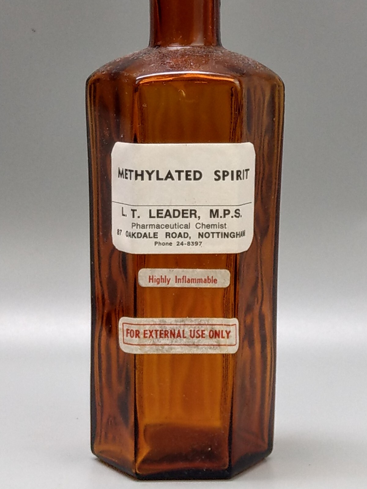 Vintage brown glass chemist bottle with label: Methylated Spirit L.T. Leader