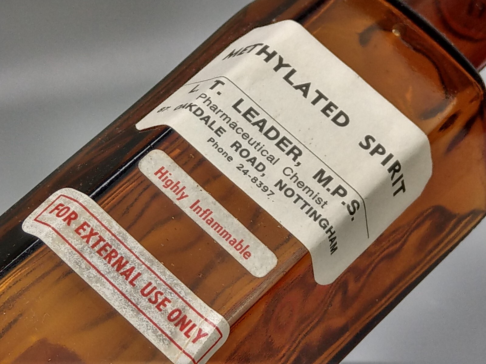 Vintage brown glass chemist bottle with label: Methylated Spirit L.T. Leader