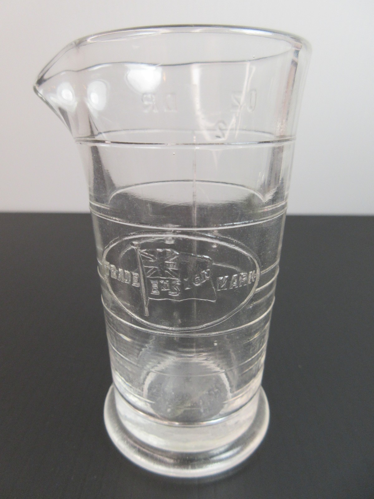 1930’s ENSIGN UK Footed Glass Embossed APOTHECARY MEASURE BEAKER Ounces & Drams